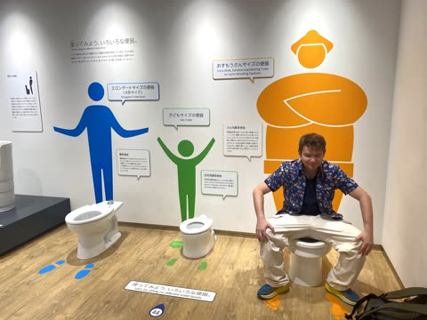 Man sitting on a small toilet in a bathroom display.