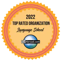 An orange and yellow award seal from GoAbroad.com for a 2022 Top Rated Organization in the Language School category.