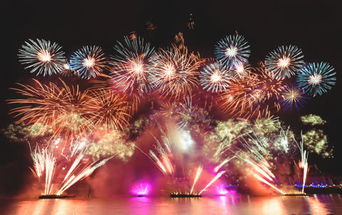 Colorful fireworks explode at night over the London Eye on the River Thames.