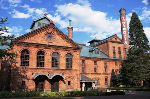 Brick building with tall smokestack, red stars, and Sapporo Beer Museum sign.