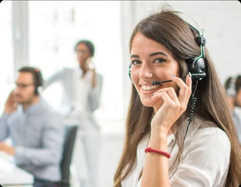 Woman wearing headset speaks at office desk.