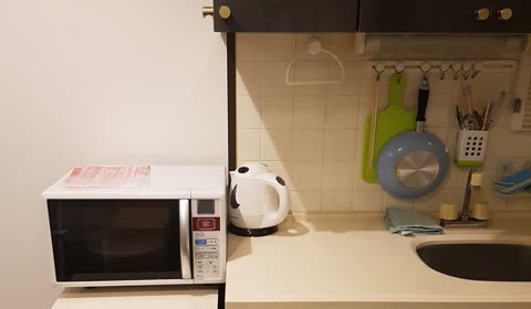 Microwave, electric kettle, and kitchen utensils sit on a countertop.